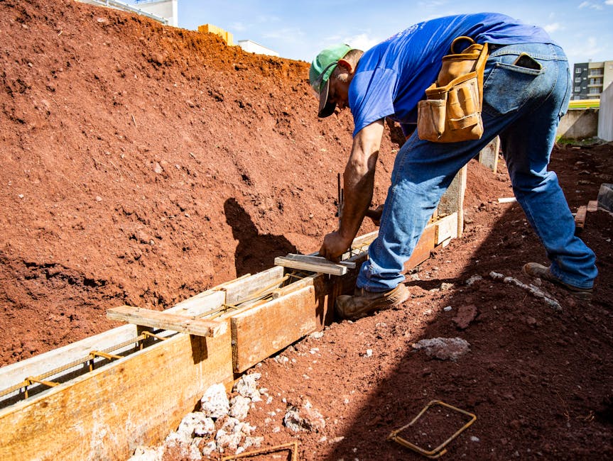 pracownicy budowlani wlewający beton do szalunków fundamentowych na placu budowy