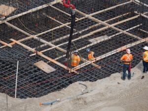 pracownik budowlany układający zbrojenie pod beton na placu budowy